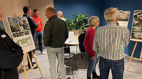 Mensen in een ruimte die kijken naar tekeningen en impressies