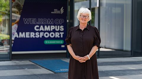 Een vrouw voor de ingang van het gebouw van het ROC.