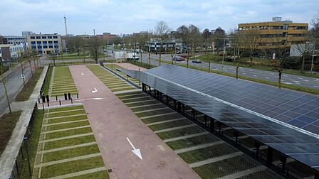 Een parkeerterrein met overdekte fietsenstalling die zonnepanelen op het dak heeft